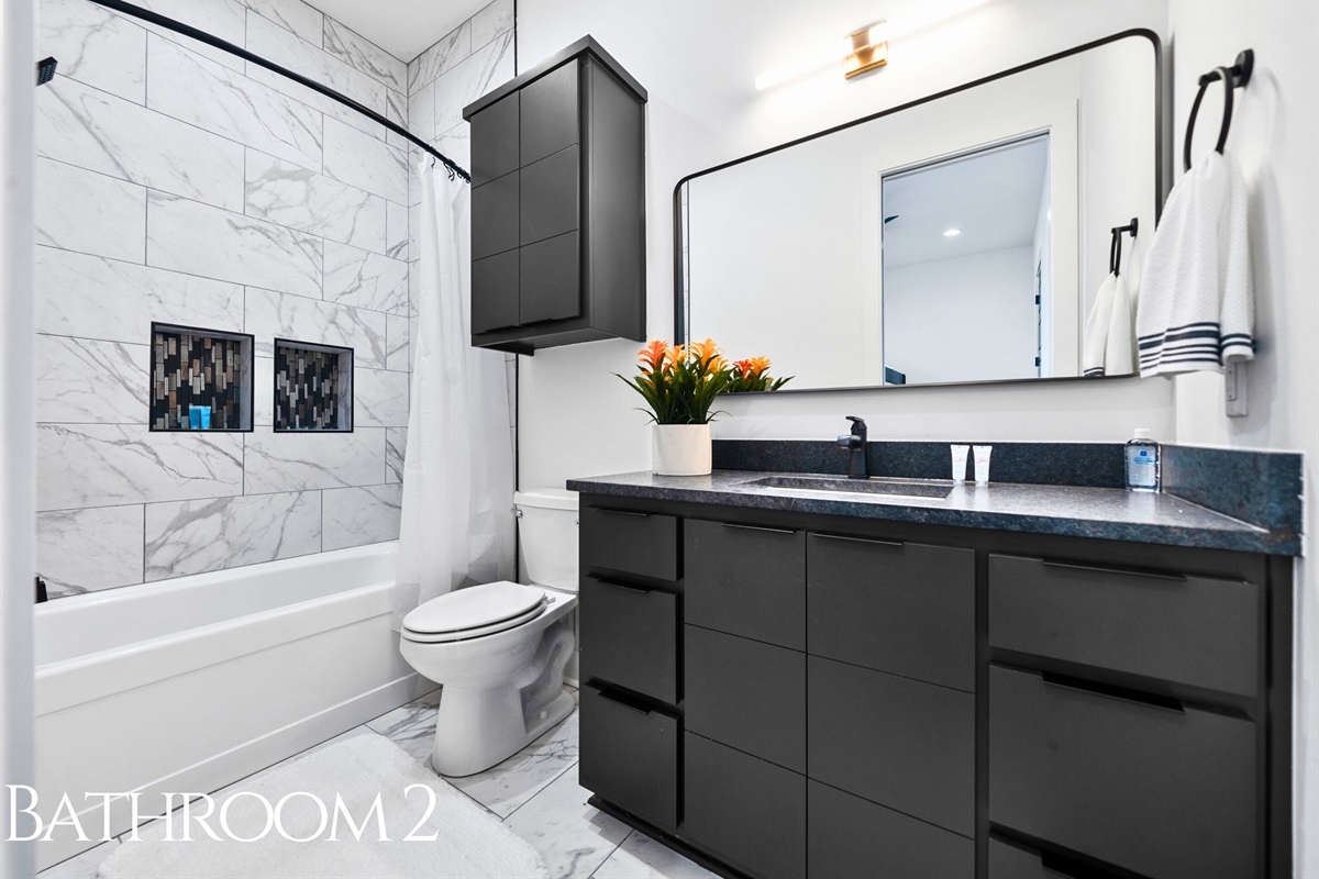 This elegant bathroom offers a fresh, modern design with sleek tilework, a shower-tub combination, and stylish fixtures for a polished yet functional look.