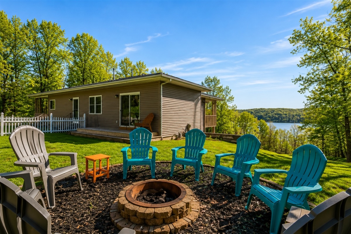 Relax lakeside in this cozy outdoor space, featuring a warm fire pit and colorful Adirondack chairs, all set against the stunning backdrop.