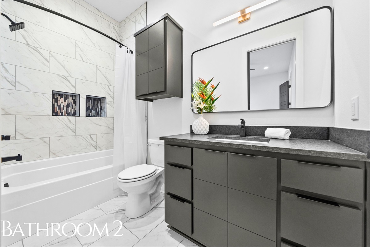 This bright and modern bathroom features sleek fixtures, elegant tilework, and a versatile shower-tub combination for ultimate convenience.