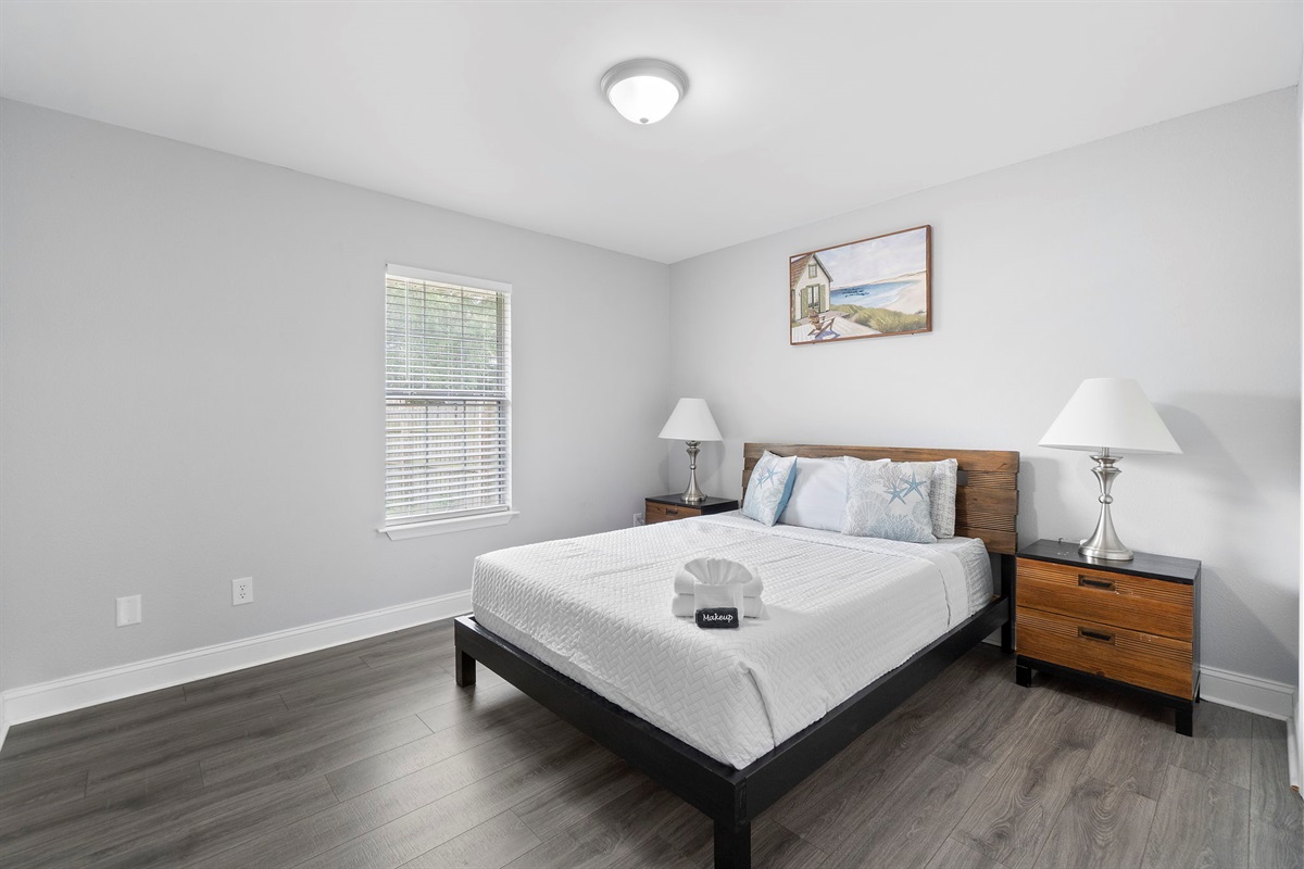 This cozy and stylish bedroom offers a queen-sized bed with soft white linens, warm wood furniture, and calming decor to ensure a restful night's sleep.