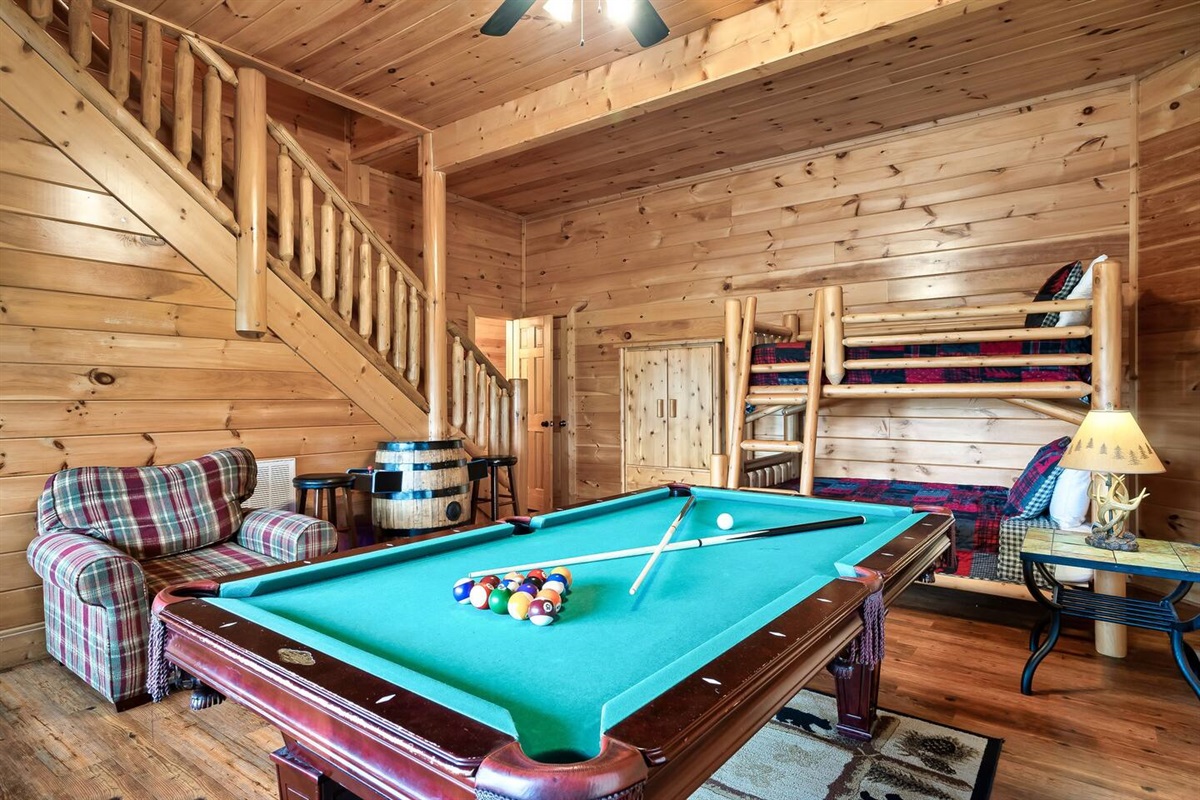 Downstairs game room which doubles as the 4th bedroom with twin over full bunk beds and a pull out sofa bed.Pool table and multicade pictured as well as the armoir and  entrance to the half bath at the bottom of the stairs.