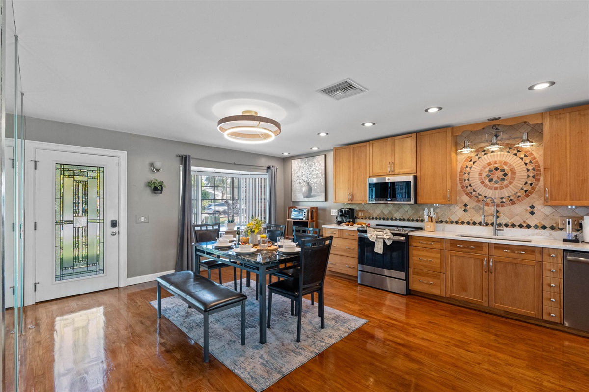 Soft recessed lighting and natural sunlight fill the room, highlighting the warm wood tones and gleaming countertops.