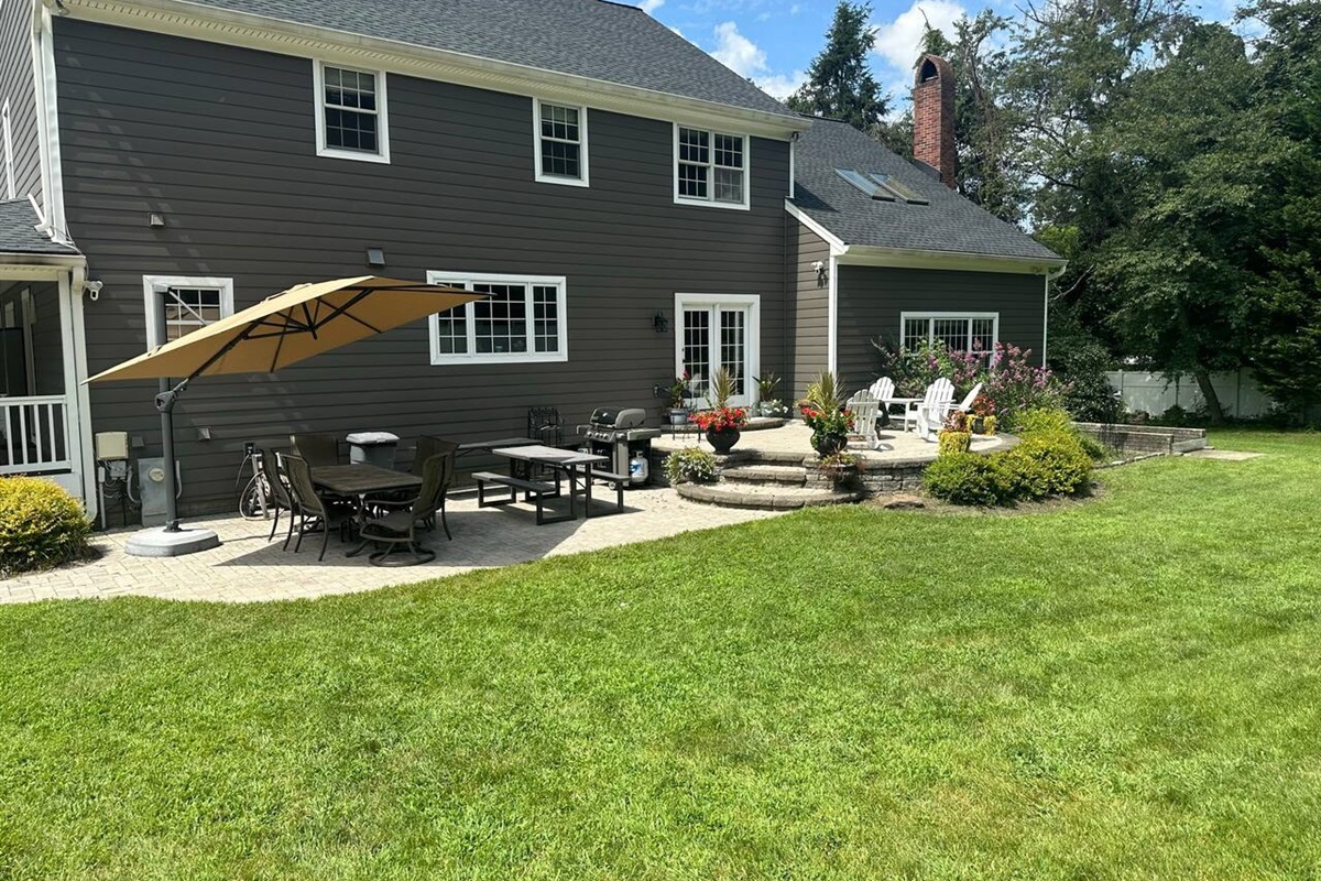 Patio on the back of the home is very large with a large cantilever umbrella, large tables to eat on, and a full grill, with additional seating on the higher patio.