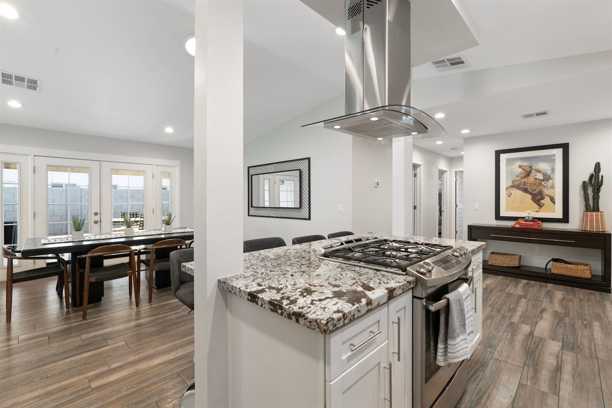 Modern open-concept kitchen and dining area featuring granite countertops, sleek appliances, and stylish wood flooring, perfect for entertaining.