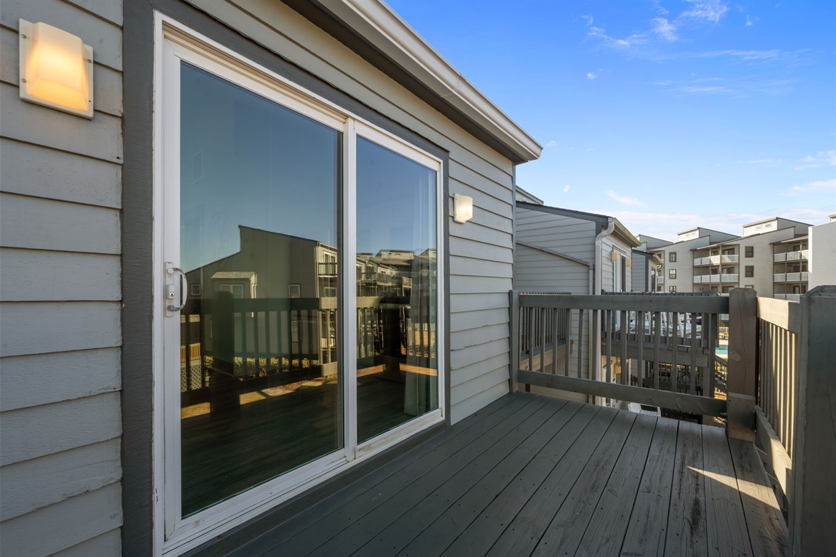 Upper-level deck with sliding door access and open coastal views&mdash;great for fresh air, quiet moments, and relaxing between beach outings