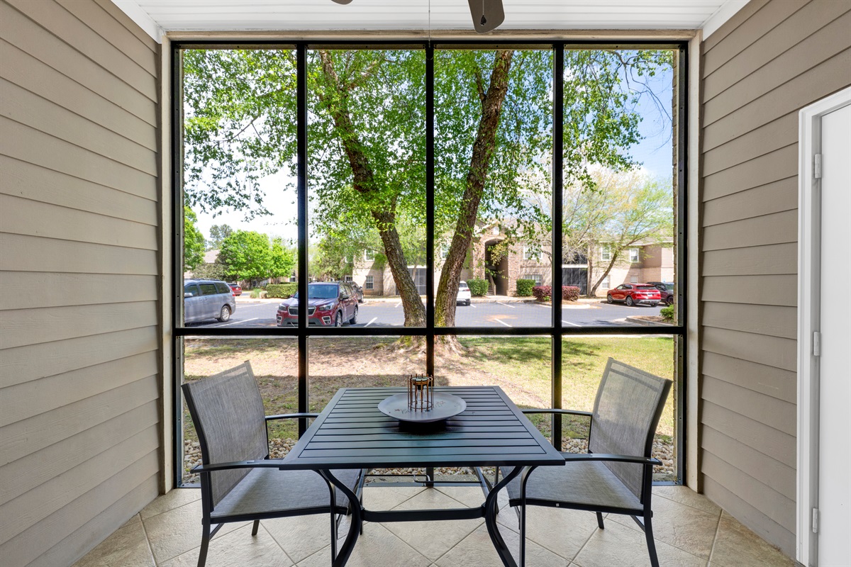 Covered screened in porch area with seating and table 