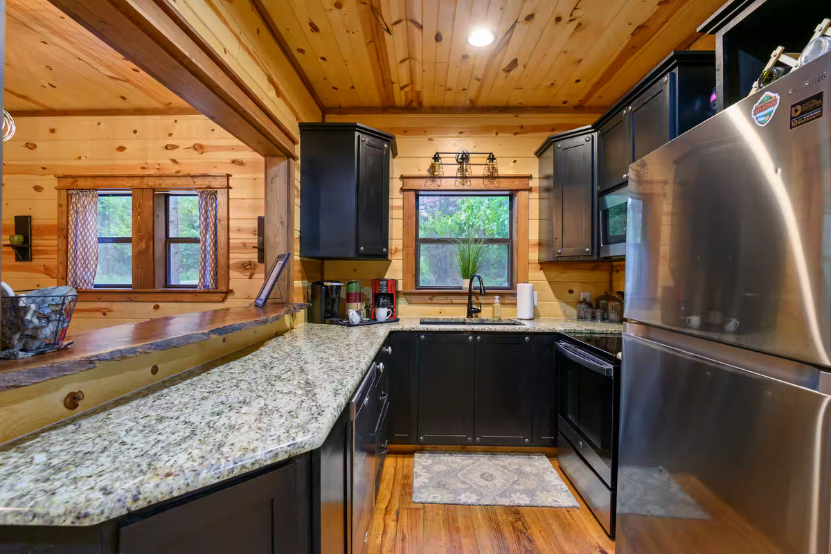 Kitchen: Sleek black cabinets and granite counters invite culinary adventures amidst rustic charm!