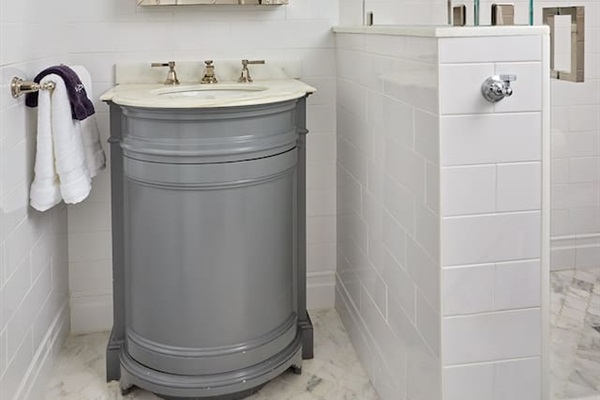 Indulge in the beauty of this ensuite bathroom, featuring luxurious Carrara marble floors, a spacious walk-in shower, a Restoration Hardware medicine cabinet, and elegant Kohler polished nickel faucet and shower fixtures.