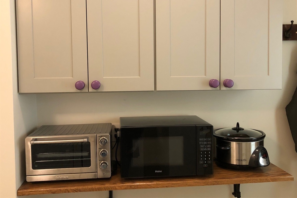 Toaster oven, microwave, and crock pot located in the laundry area. 