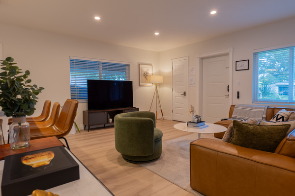 Living room with large TV, natural light, and comfortable seating for groups