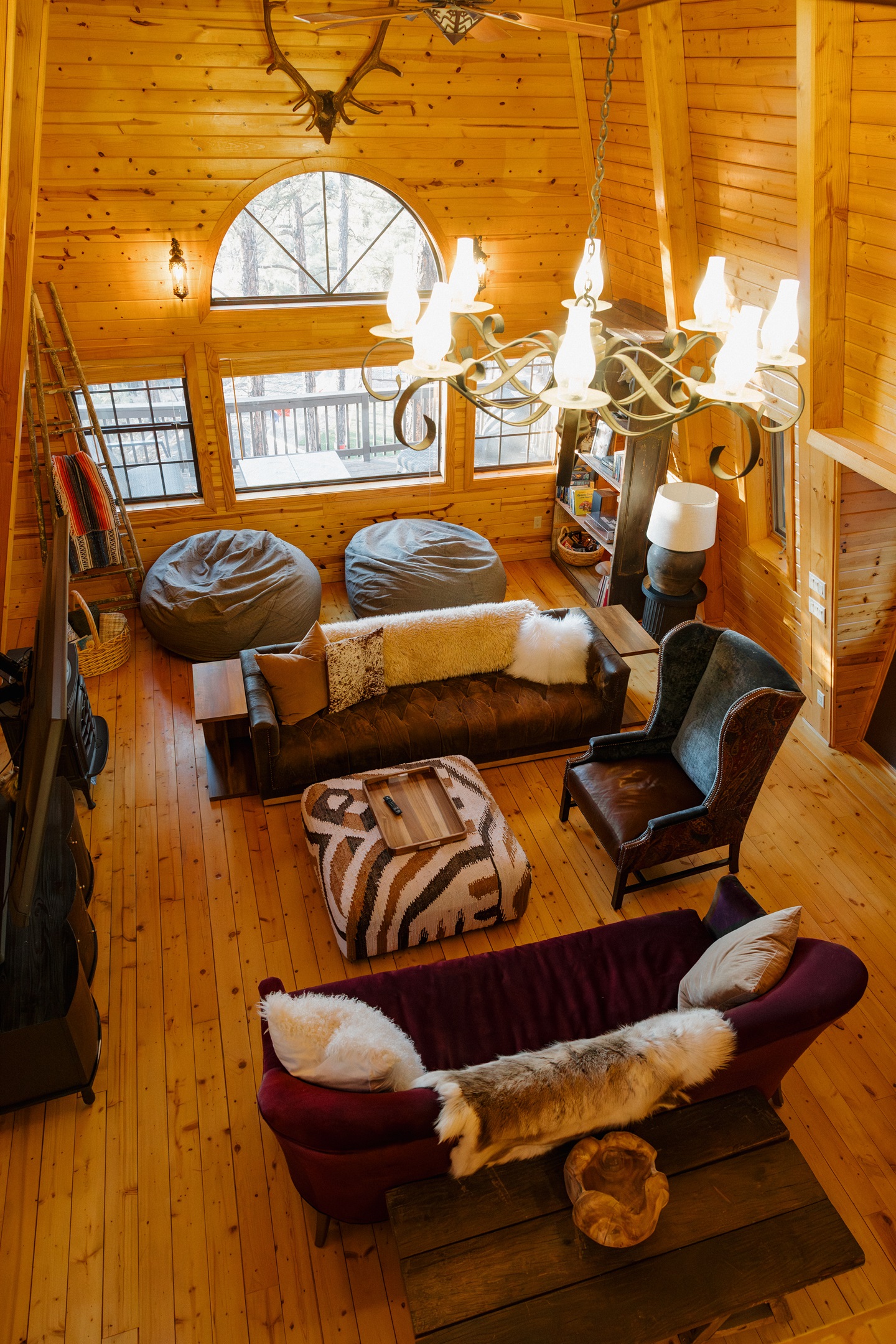 The dramatic living space at Poppywood Pines showcases soaring A-frame architecture with gothic western style. This unique Show Low cabin features cozy seating, statement chandelier, and mountain views, perfect for relaxing after White Mountains adventures