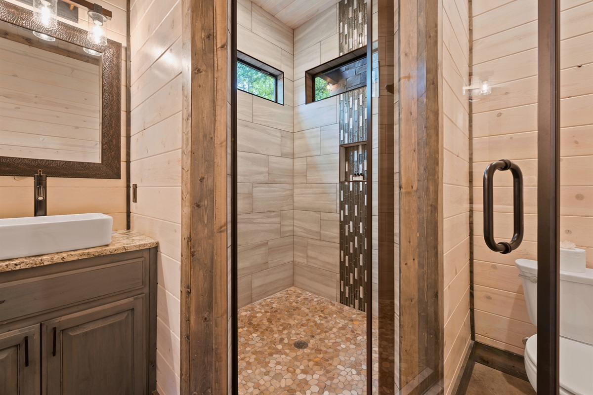 A sleek bathroom with a spacious walk-in shower and modern touches is complemented by natural light streaming in from the high windows.