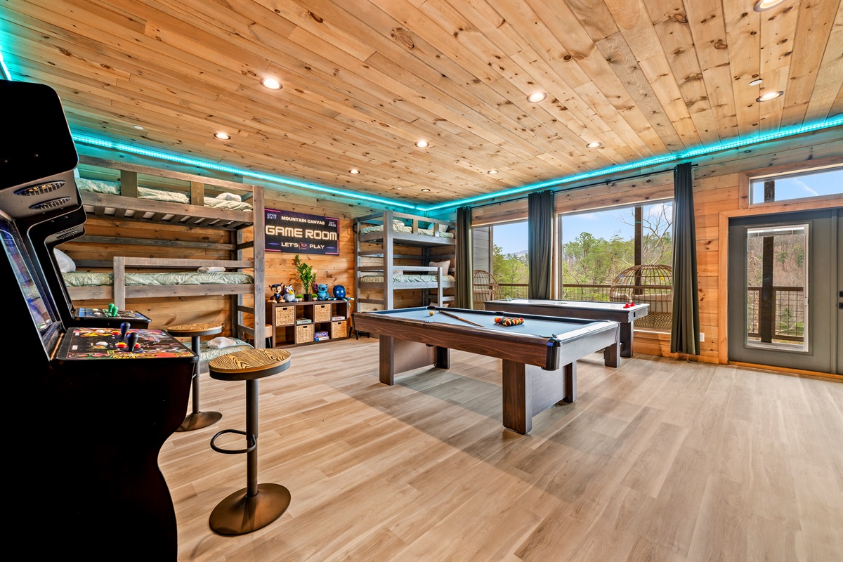 Downstairs fun zone with pool table, air hockey, 2 arcade machines, pub seating, & board games. Bunkspace with 6 twin beds. Large windows bring in the mountain views and patio access makes it easy to continue the fun outside.