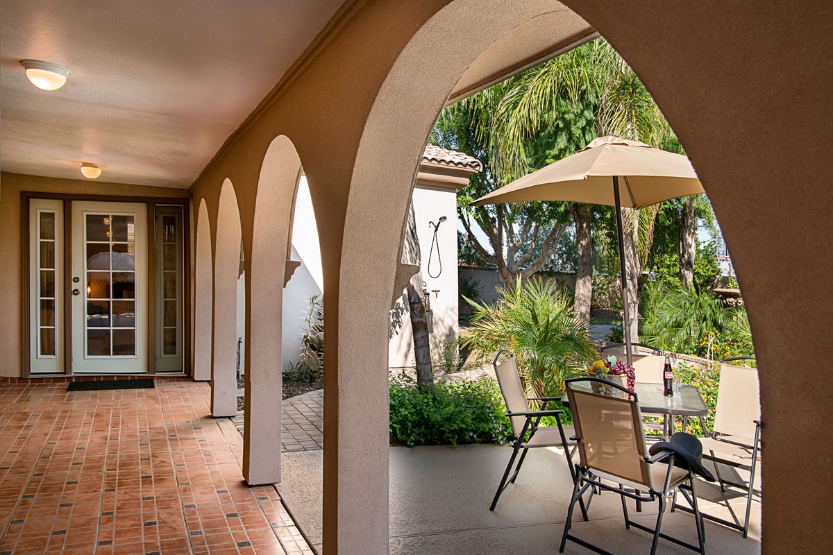 Lounge beneath graceful arches with views of the sparkling pool and blooming desert flowers in this serene outdoor living space.