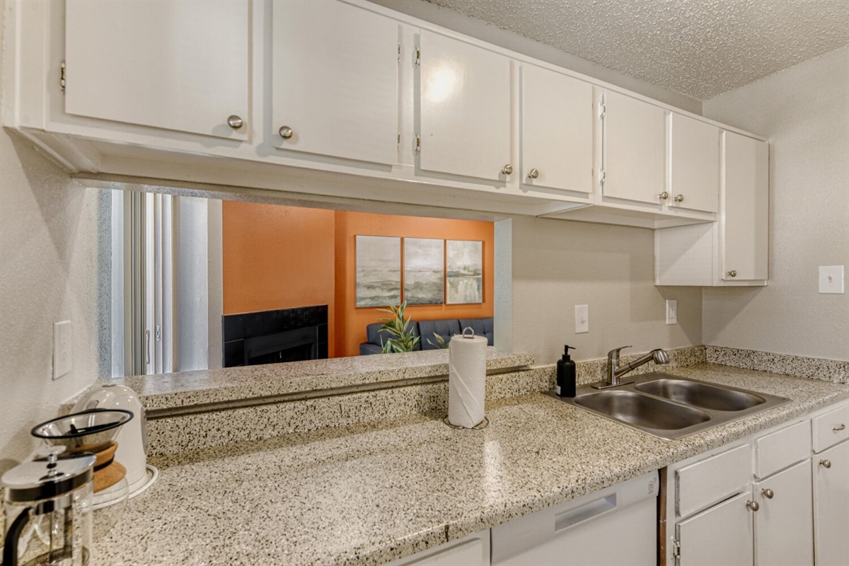 Cozy kitchen with a clean, bright design and a peek into the living space.