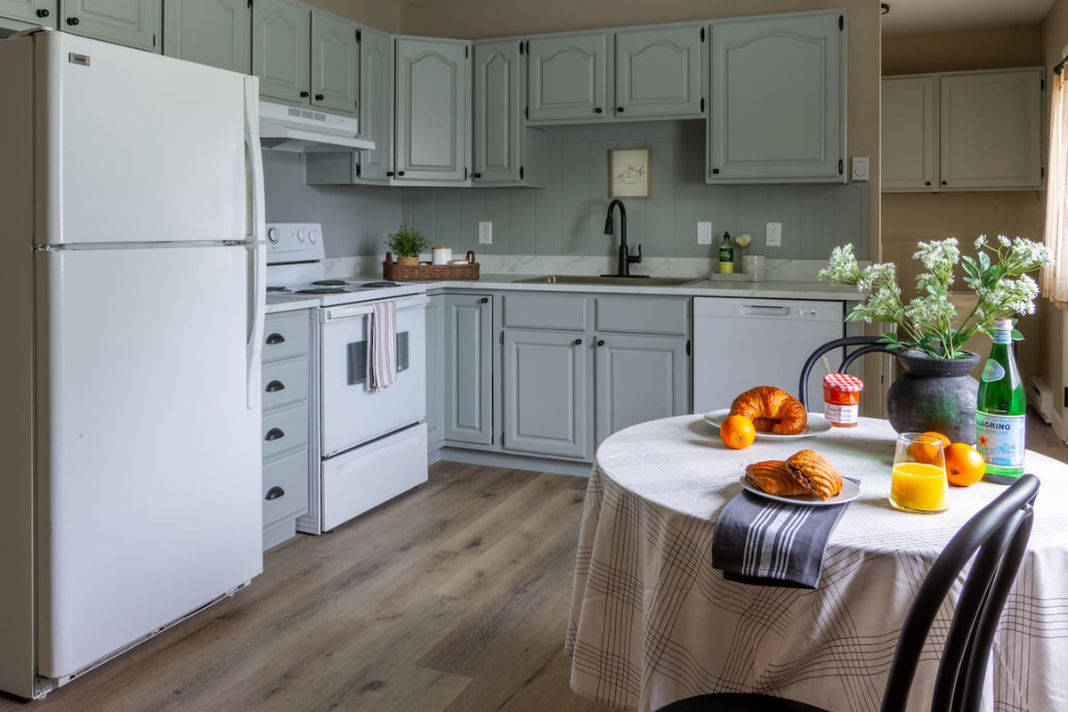 Sage cabinetry and classic finishes give the kitchen a cheerful, homey character.