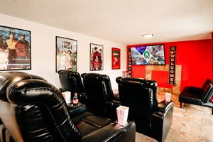 A sleek black theater chair stands out against a bold red wall, ready to embrace you into the world of cinema. The perfect seat for every movie enthusiast seeking comfort and style.