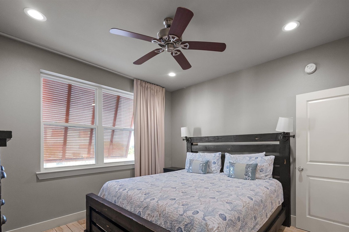 Main level bedroom with king bed, ceiling fan, TV and en-suite bathroom  