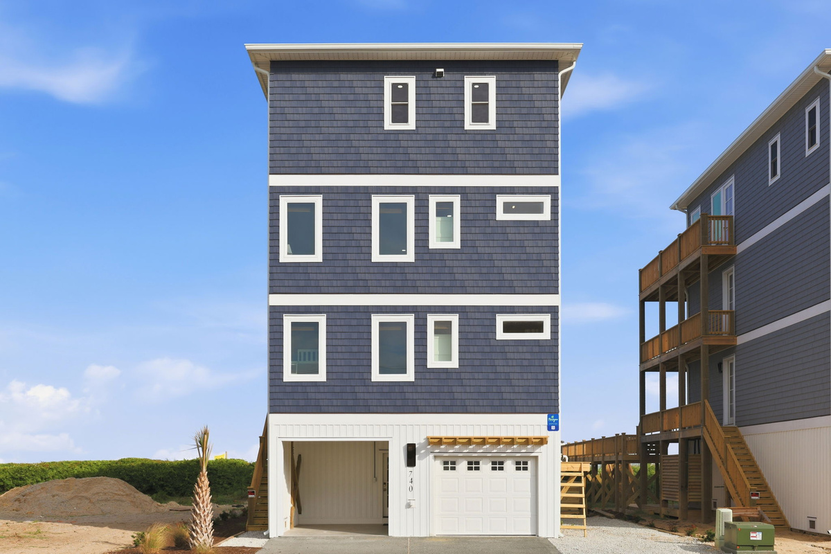 Front exterior elevation of our home featuring multi-level decks, garage parking, and direct beach access walkway alongside neighboring properties
