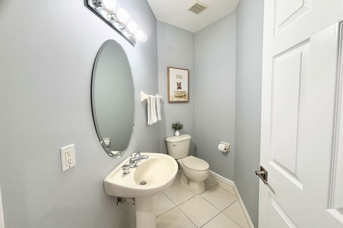 Convenient half bathroom with pedestal sink, tile flooring, and clean modern finishes.