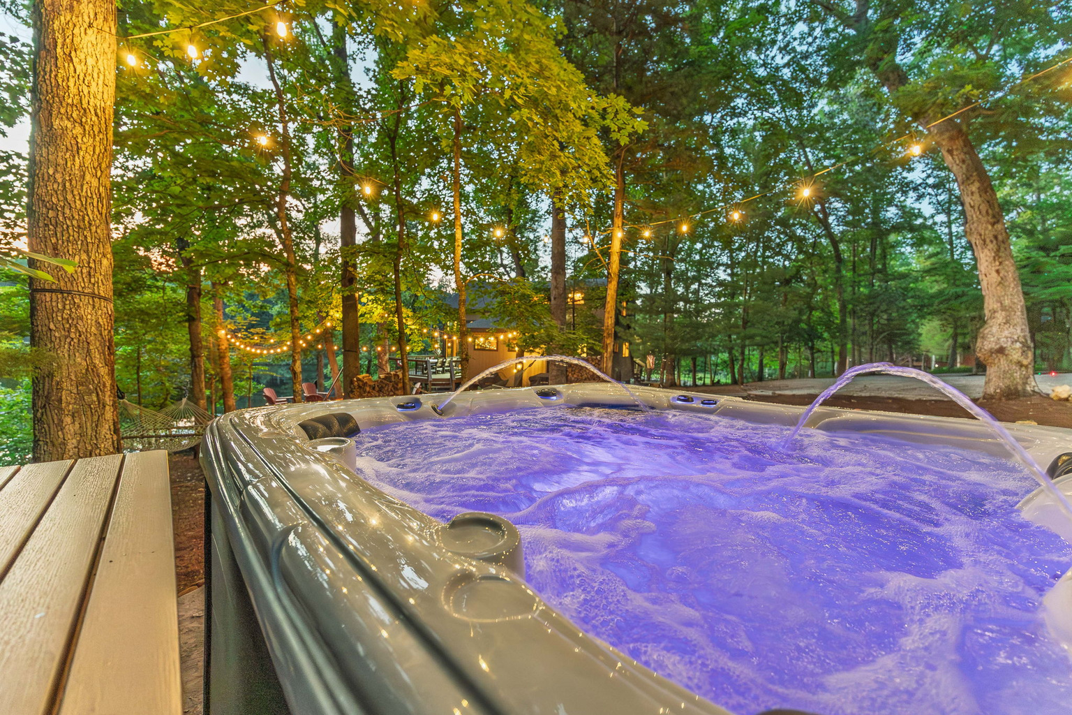 Relax in the lakeside hot tub beneath string lights and the trees.