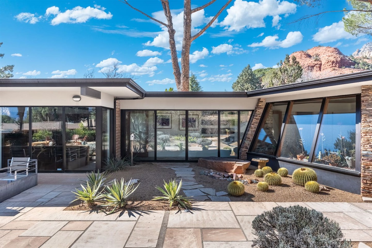 Bright interior courtyard featuring clean architectural lines, expansive glass walls, and desert landscaping with cacti and agave.