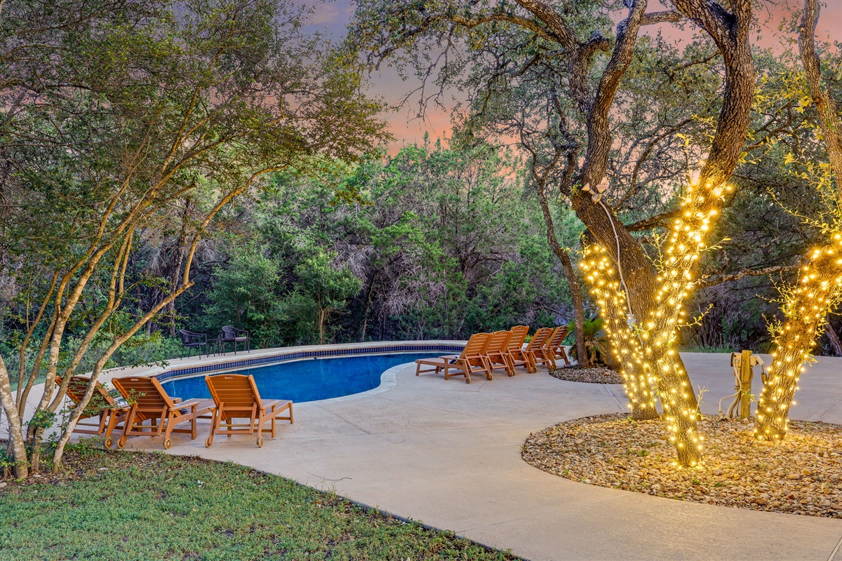Twinkling lights wrap around the trees in this cozy pool corner, creating a magical and romantic atmosphere for nighttime dips.
