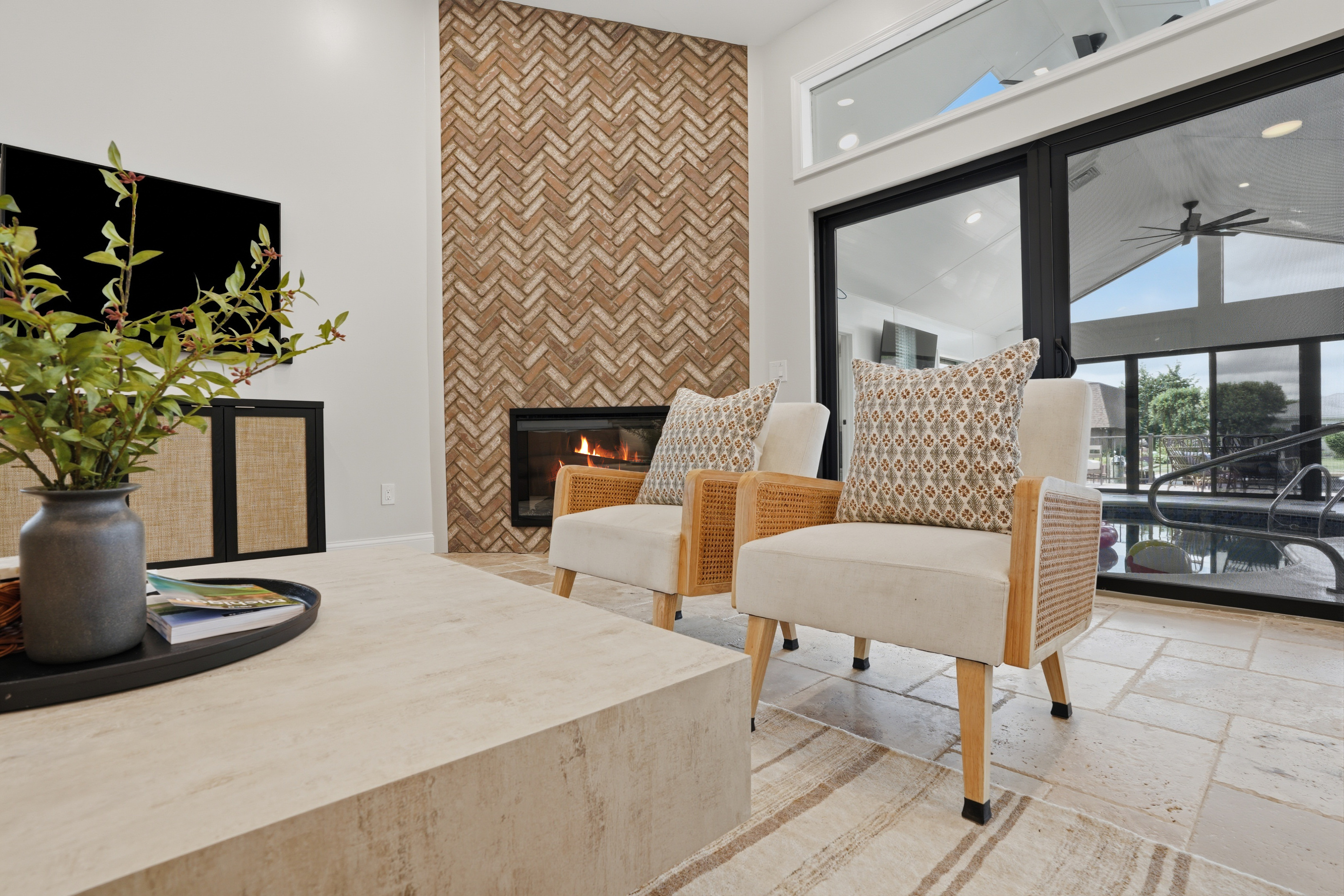 Modern living room with a stylish fireplace, textured accent wall, and comfortable seating. Bright, open space with warm finishes and a cozy yet upscale atmosphere—perfect for relaxing or entertaining.