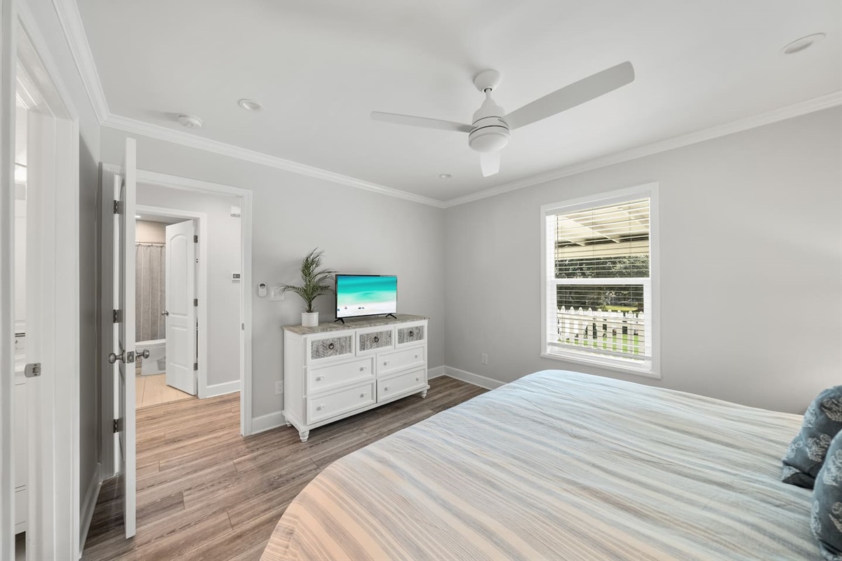 Master bedroom of Unit B with a king bed, TV and half bathroom. 
