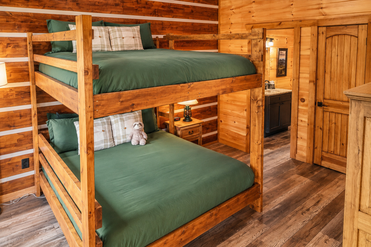 Oversized log bunks dressed in forest green turn bedtime into a camp adventure.