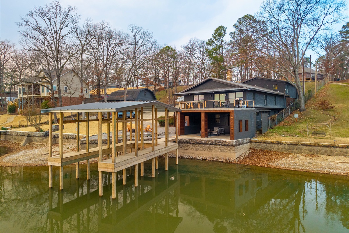 A wider view of the home and dock highlights just how close the house sits to the water&rsquo;s edge.
