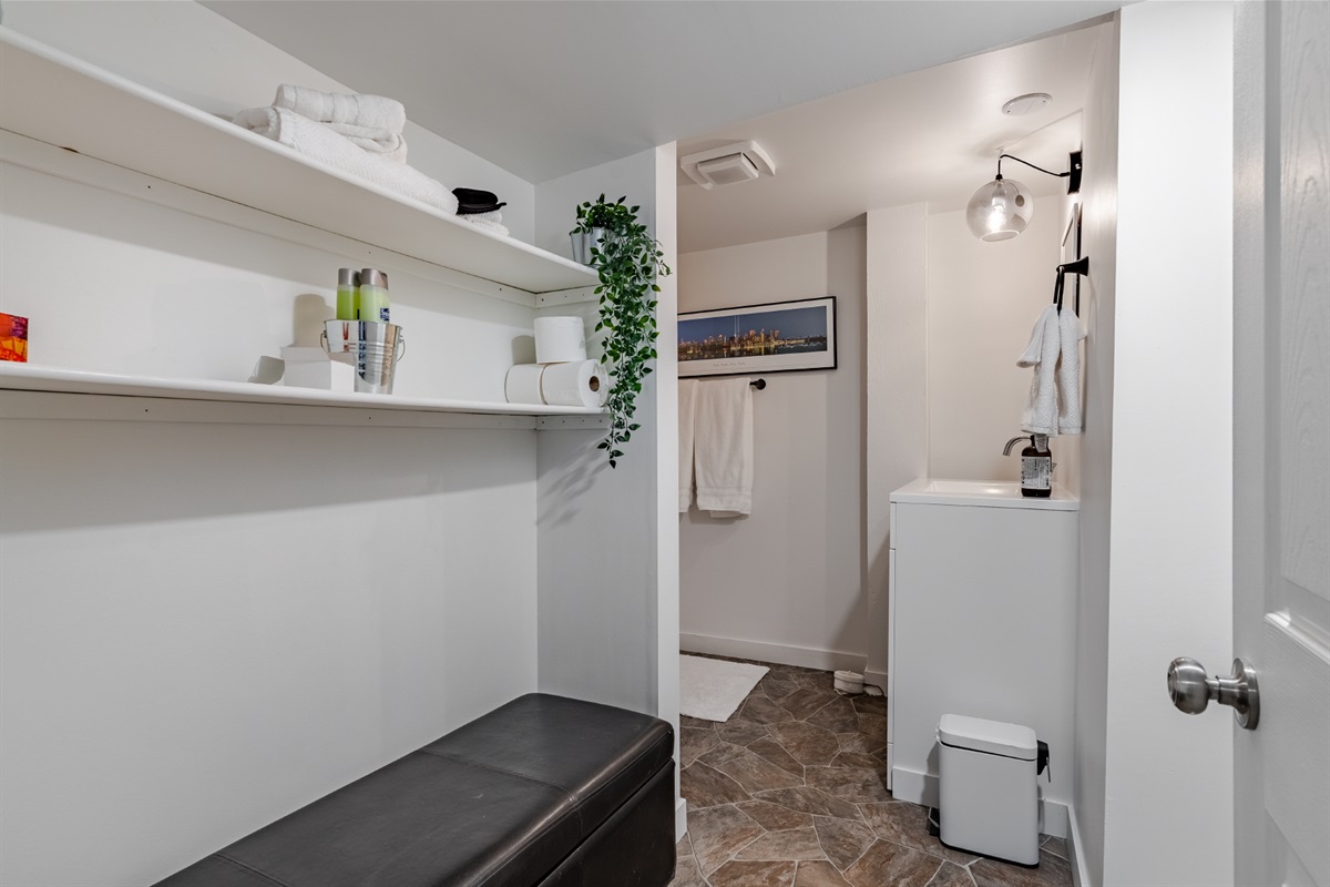 Bathroom with walk-in shower, towels, and open shelving for personal items.