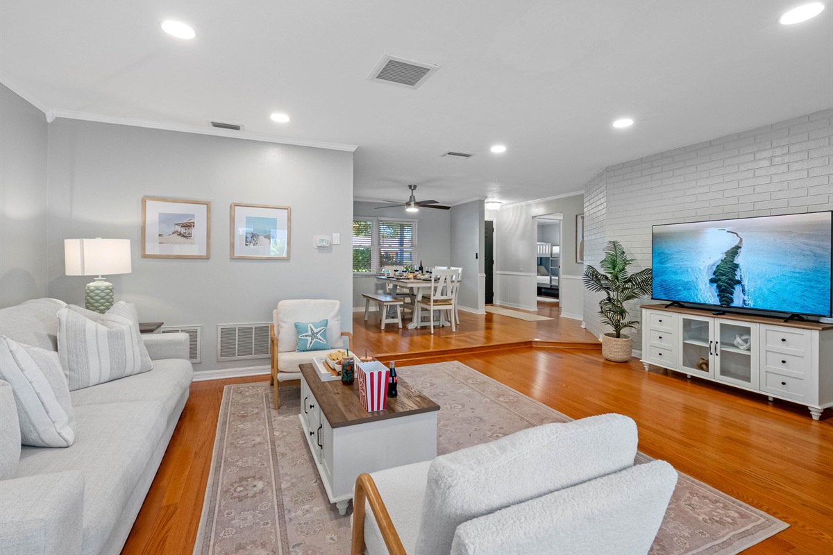Stretch out and unwind in this spacious living area featuring warm wood floors, serene tones, and comfy furniture perfect for family time or movie night.