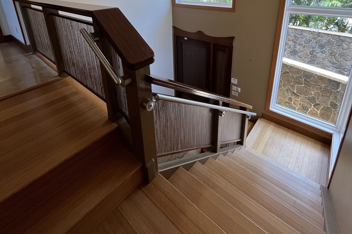 Wide wooden staircase with stainless steel handrailing