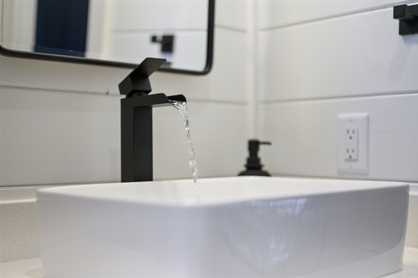 The guest bathroom features sleek black fixtures and crisp white shiplap for a clean, modern look.