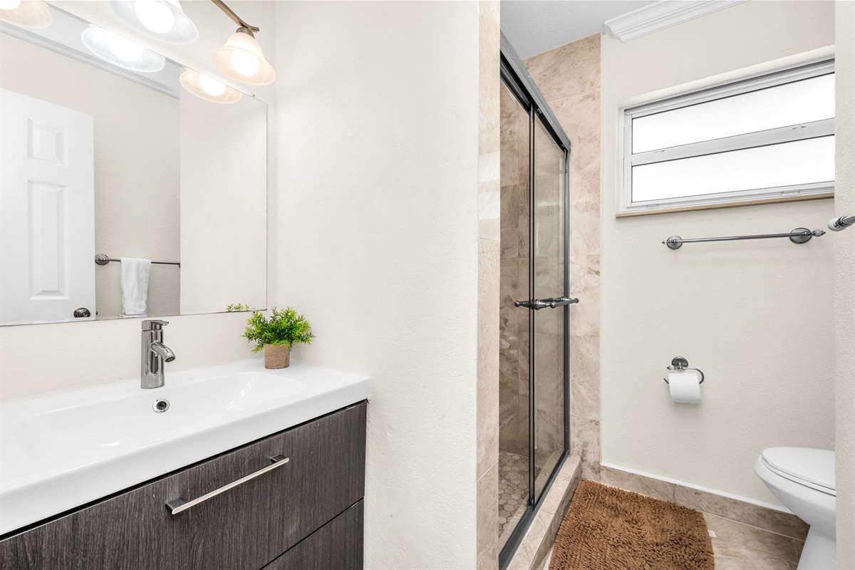 Updated bathroom featuring a glass walk-in shower, modern vanity, and fresh design—perfectly positioned between the first two bedrooms.