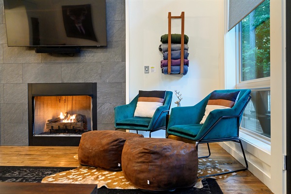 Sink into warmth and quiet — glowing fire, soft textures, and forest views that make this nook the perfect place to slow down