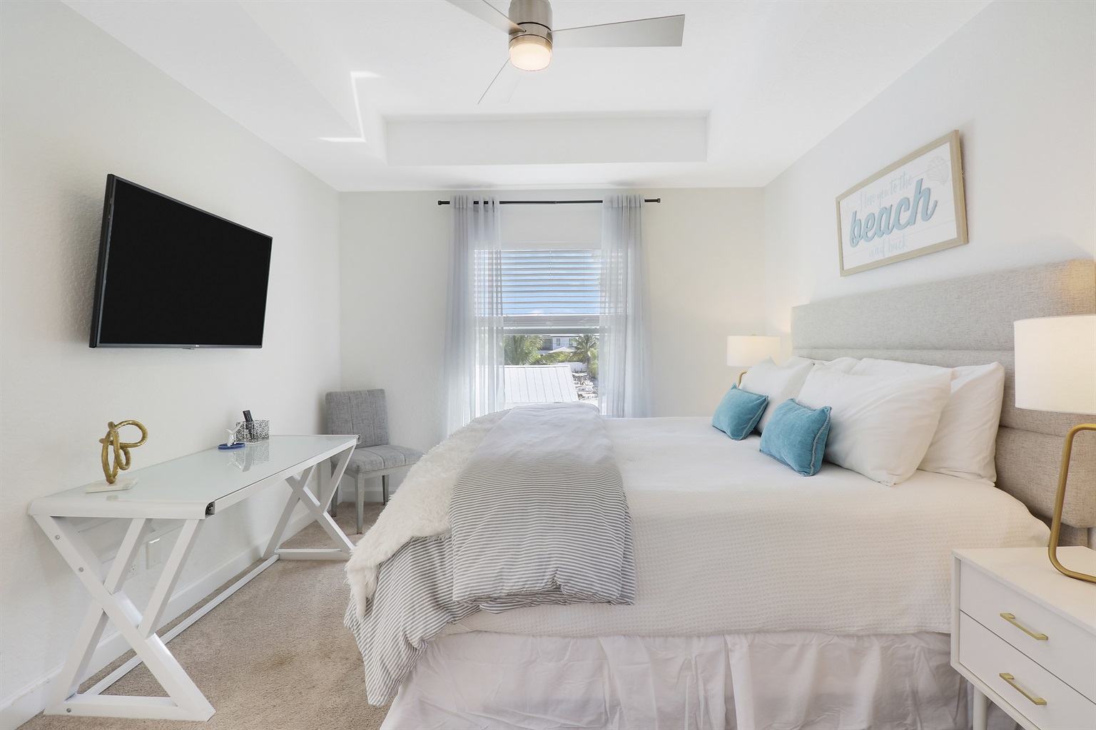 The master suite with pool and courtyard view, dedicated workspace, large walk in closet, wood hangers, luggage rack, dresser, and 55" tV