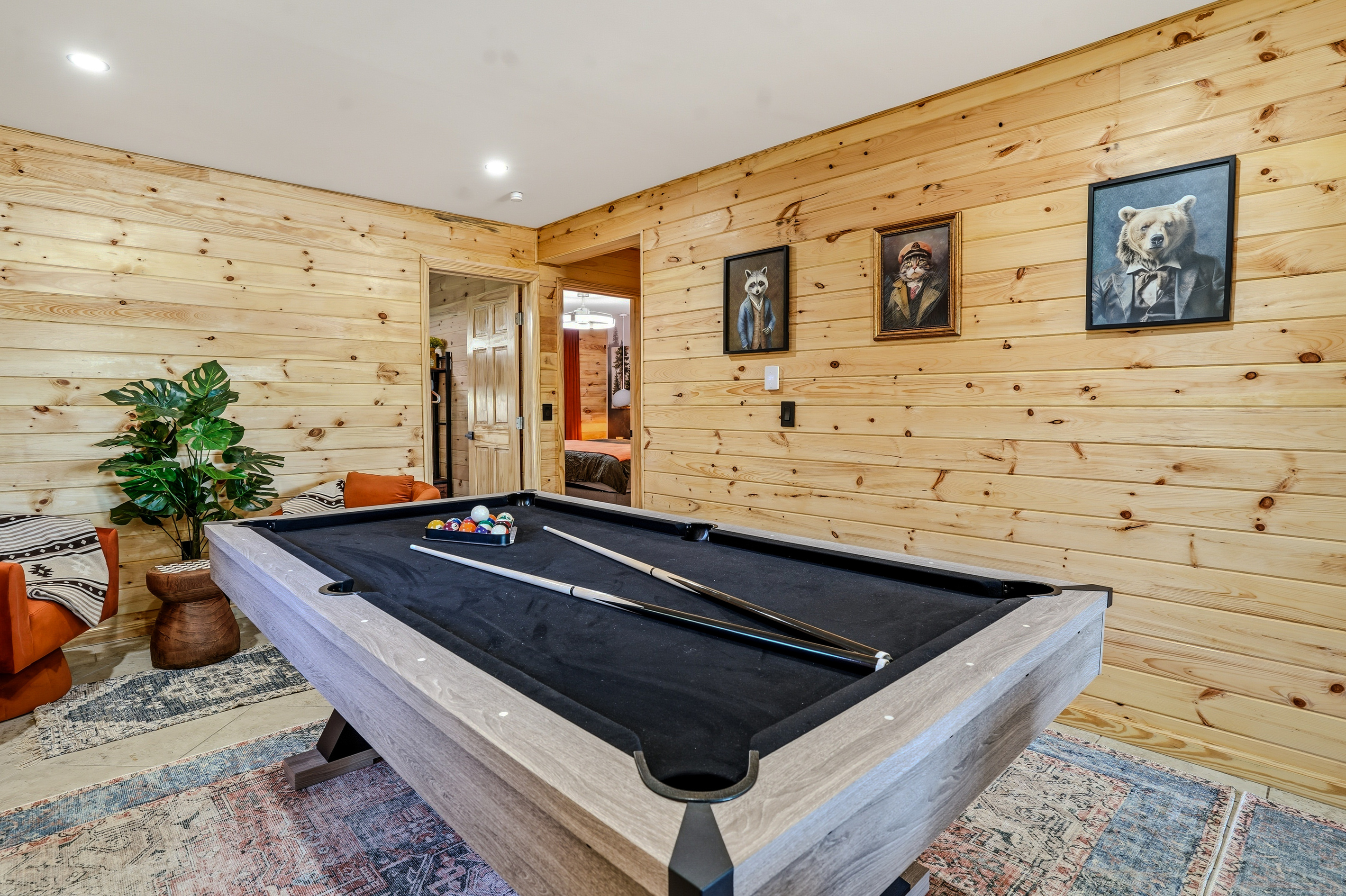 Full-size pool table in the game room with wood-paneled walls and art prints