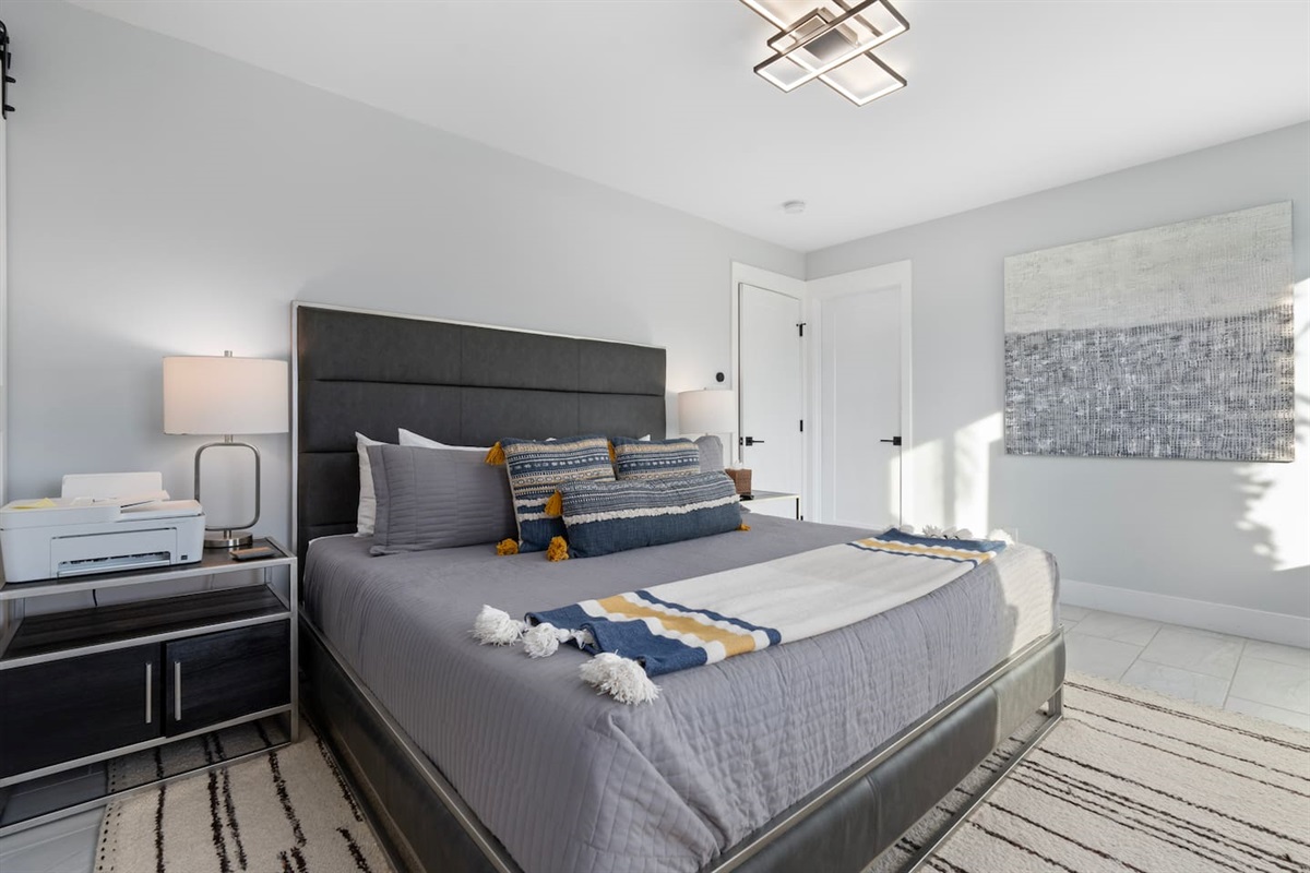 Pops of mustard yellow and textured blue in the pillows add a playful yet calming contrast to the sleek grey bedding.

