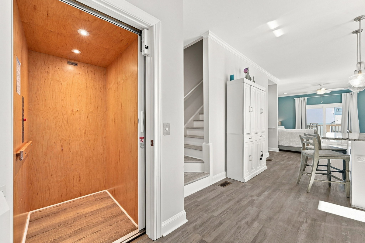 Convenient private elevator interior with wood paneling, situated right off the main hallway and stairwell for easy access across floors.   