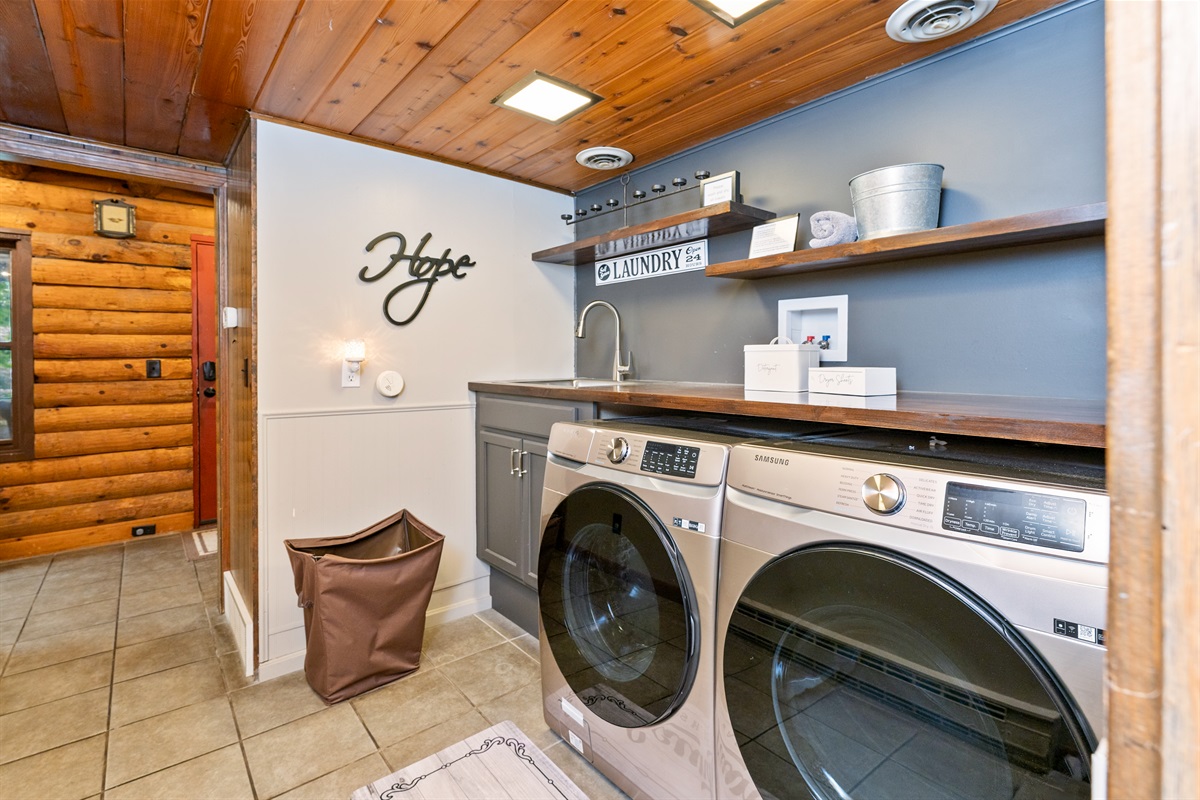 Updated main floor laundry space with modern Samsung washer/dryer, farmhouse shelving, and deep sink for all your vacation needs.