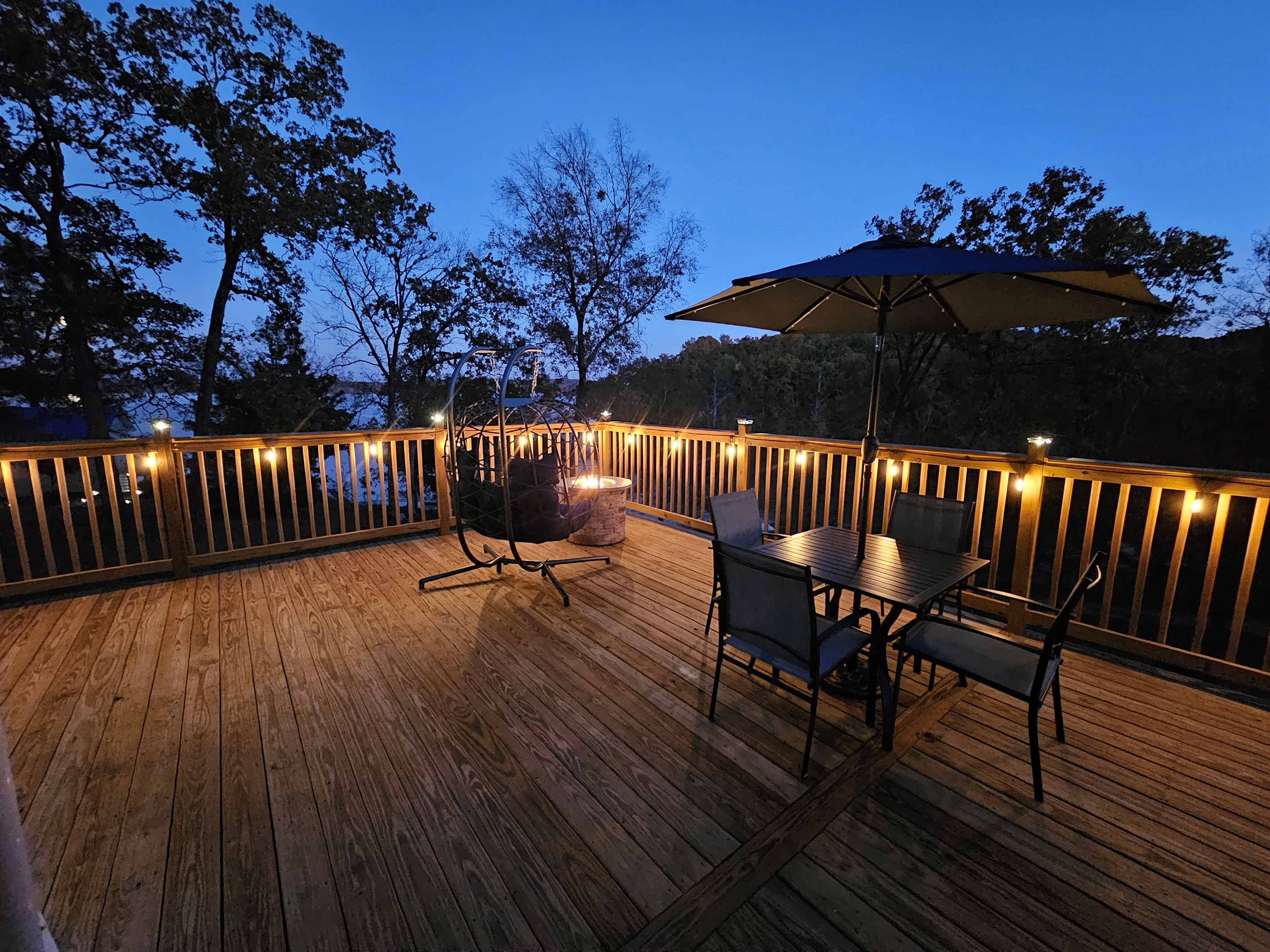 Spacious nighttime deck with café seating, glowing string lights, and serene lake views — perfect for relaxing under the stars