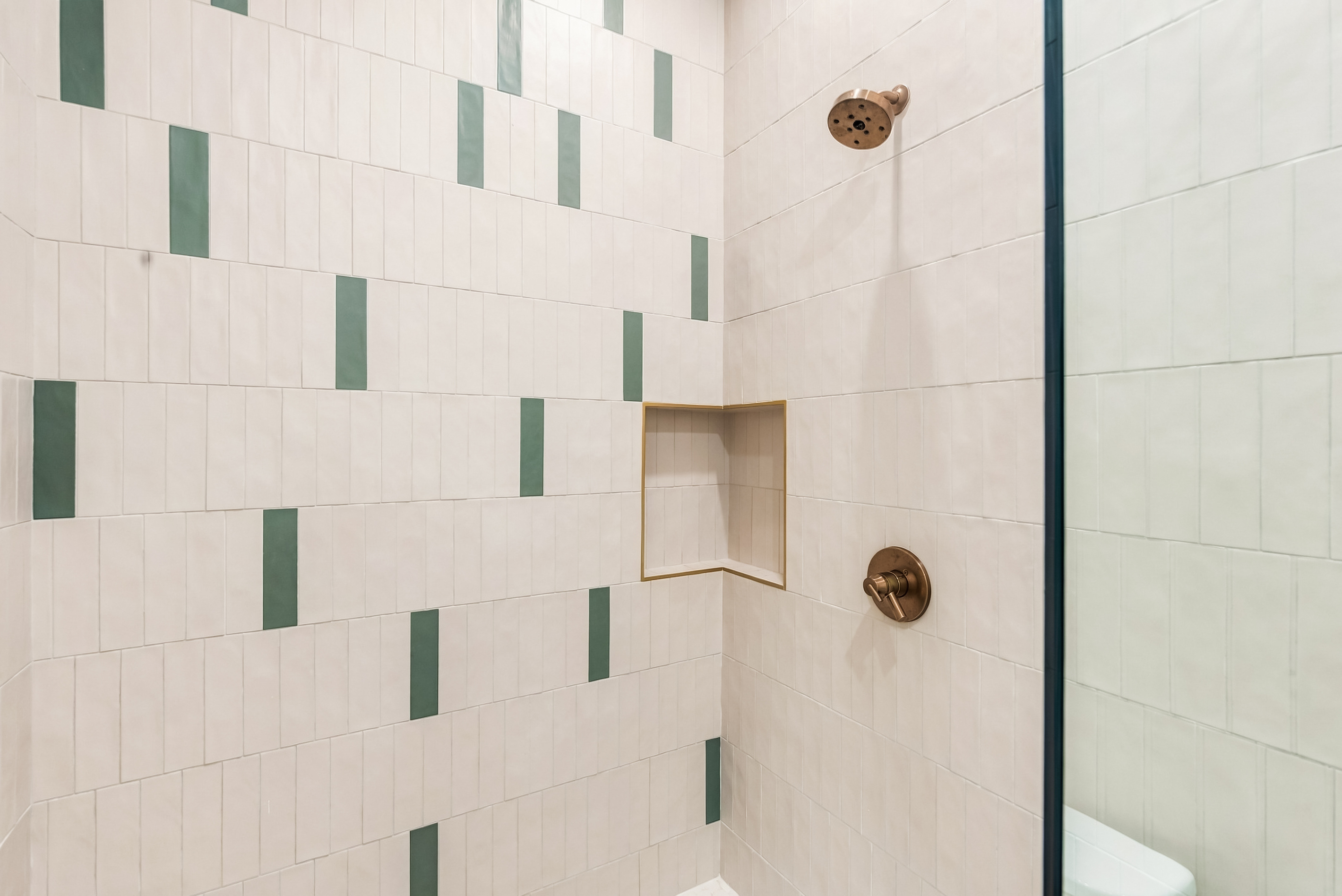 Glass walk-in shower with a built-in niche, finished in playful mosaic tile.