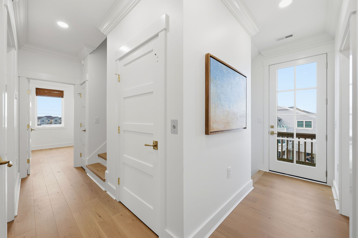 Bright entry corridor with glass door access, balcony views, and contemporary artwork accent wall