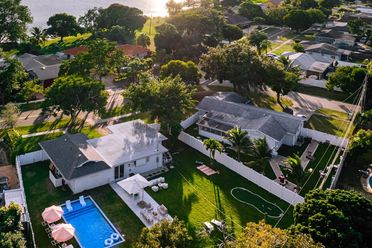 Oversized, fully fenced Palm Beach backyard featuring a heated pool, outdoor dining patio, fire pit lounge, and games.