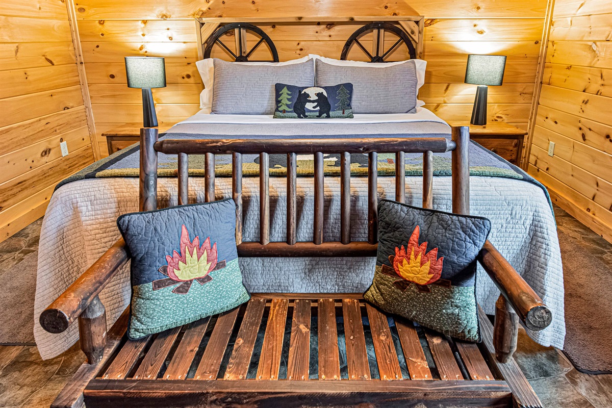 Cozy cabin vibes. Unwind and relax in this rustic bedroom, complete with a comfy bench and campfire-themed pillows.