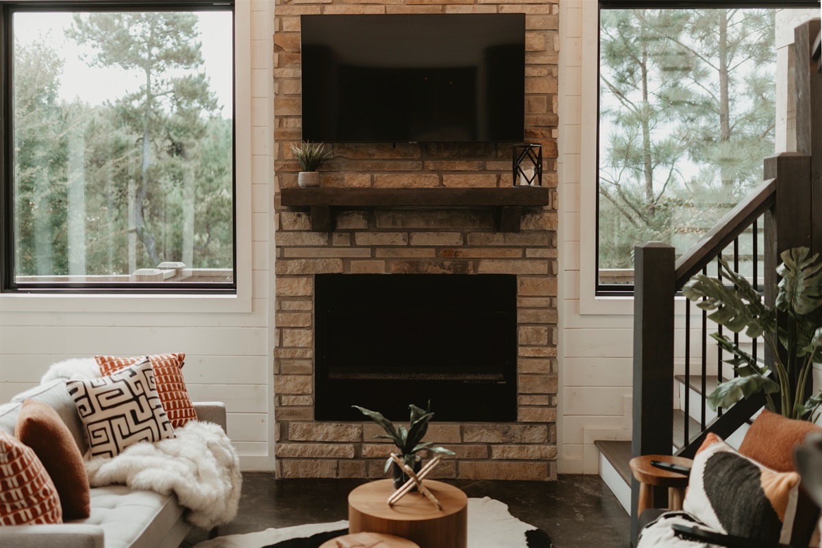 Gather in style—this stone fireplace and soaring windows frame the perfect cabin lounge. Curl up on plush seating, watch a movie, or simply enjoy forest views with the glow of the fire.