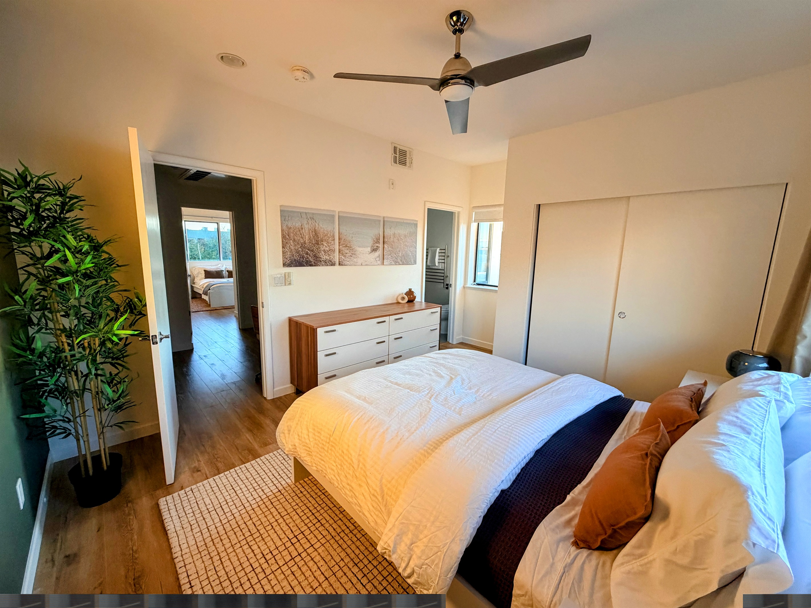 Primary bedroom with queen bed looking toward the bathroom and hallway.