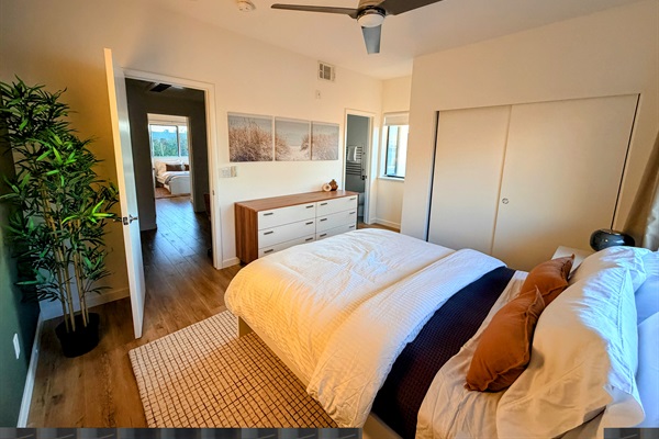 Primary bedroom with queen bed looking toward the bathroom and hallway.